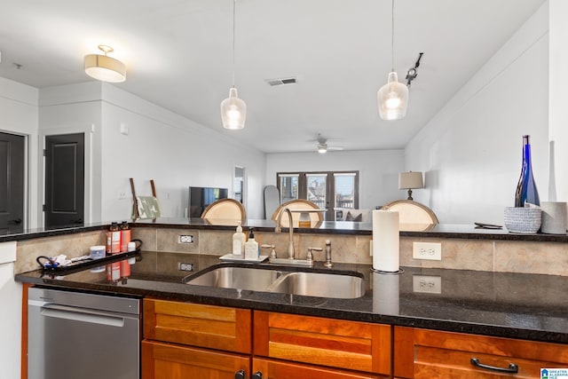 kitchen featuring a sink, visible vents, brown cabinets, dark stone countertops, and decorative light fixtures