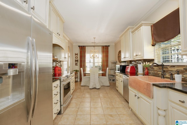 kitchen with light tile patterned flooring, stainless steel appliances, a sink, backsplash, and dark countertops