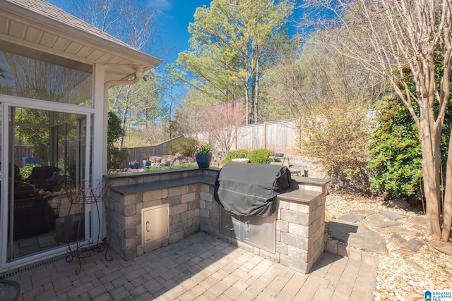 view of patio with exterior kitchen, a fenced backyard, and grilling area