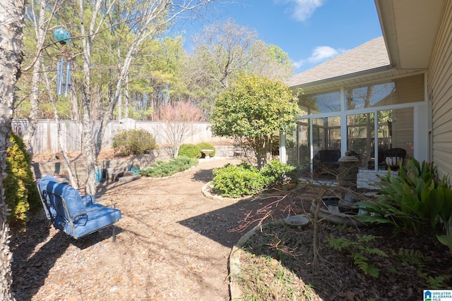 view of yard with a patio, fence, and a sunroom