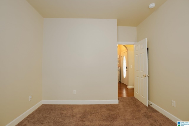 empty room featuring carpet, baseboards, and arched walkways