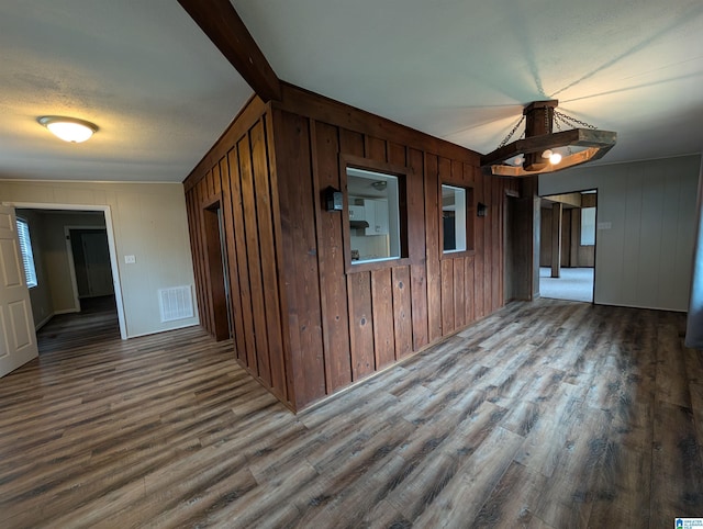 unfurnished room with wood-type flooring and beamed ceiling