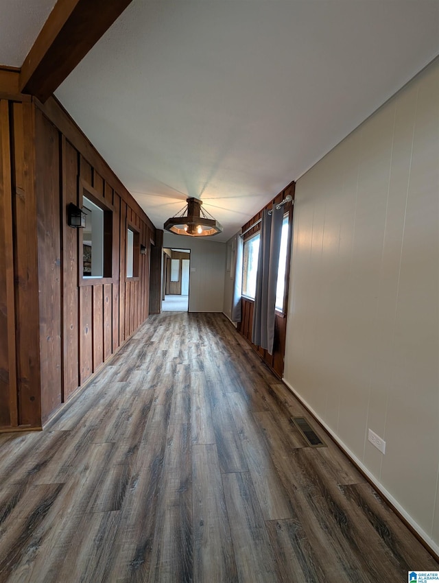 empty room with hardwood / wood-style flooring, beamed ceiling, and wood walls