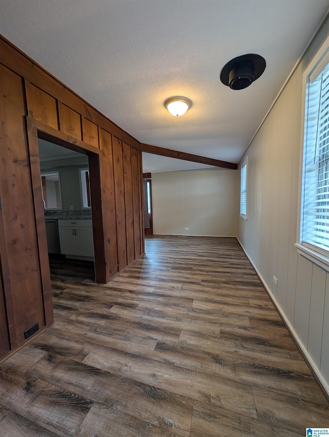 empty room featuring wood walls, dark wood-type flooring, and a textured ceiling