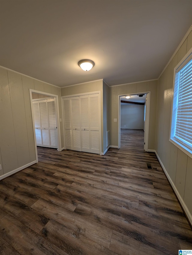 interior space with dark wood-type flooring, crown molding, and a closet