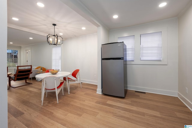 dining area with light wood-style floors, visible vents, crown molding, and baseboards