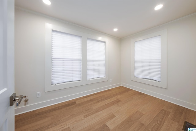 spare room featuring baseboards, light wood-style flooring, visible vents, and crown molding