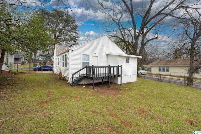 back of property featuring fence, a deck, and a lawn