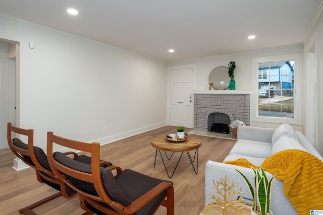 living room with recessed lighting, baseboards, ornamental molding, light wood-type flooring, and a brick fireplace