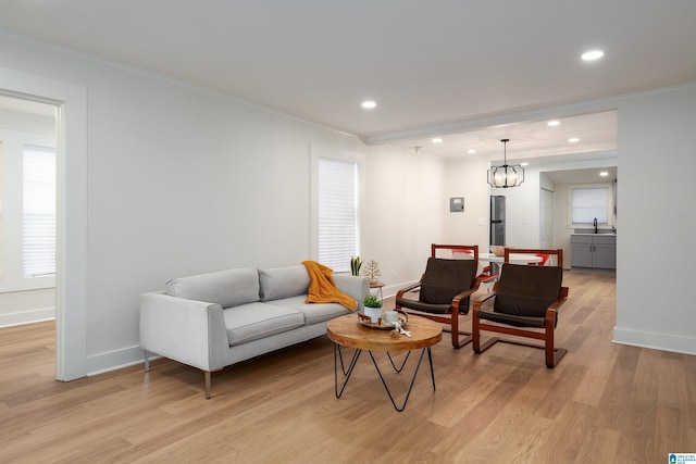 living area with baseboards, ornamental molding, recessed lighting, and light wood-style floors