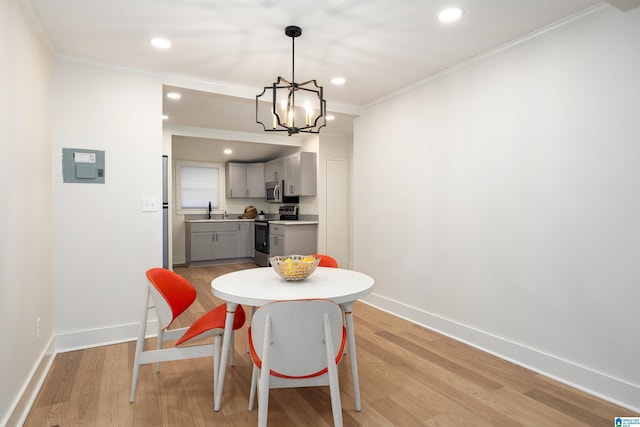 dining area with light wood-style floors, baseboards, and crown molding