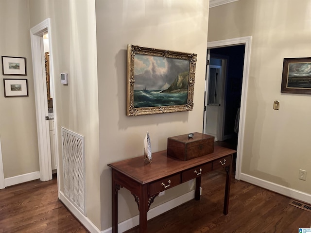 hallway featuring baseboards, visible vents, and wood finished floors