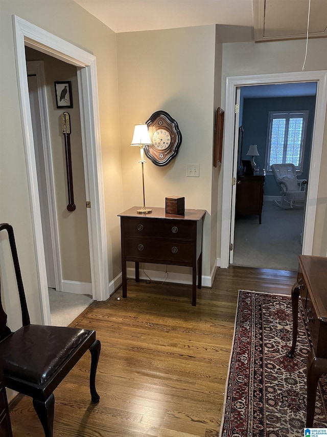 hall featuring wood finished floors, attic access, and baseboards