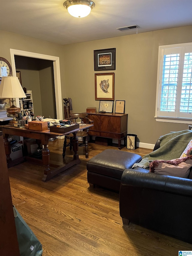 office area with wood finished floors, visible vents, and baseboards