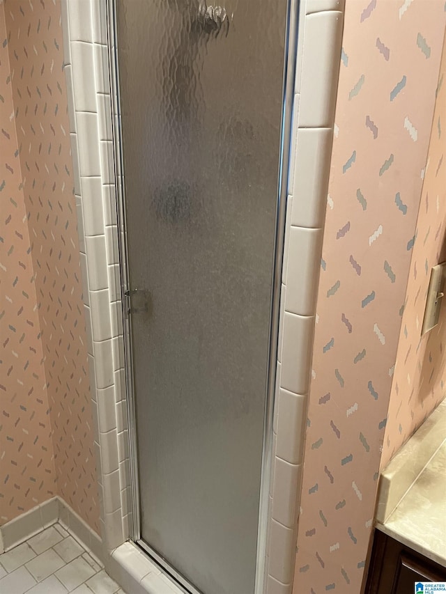 full bath featuring baseboards, wallpapered walls, a stall shower, and tile patterned floors