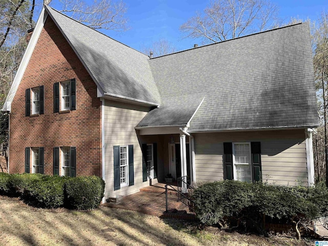 view of front of house featuring a shingled roof and brick siding