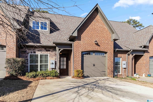 view of front of home with brick siding, roof with shingles, a garage, stone siding, and driveway