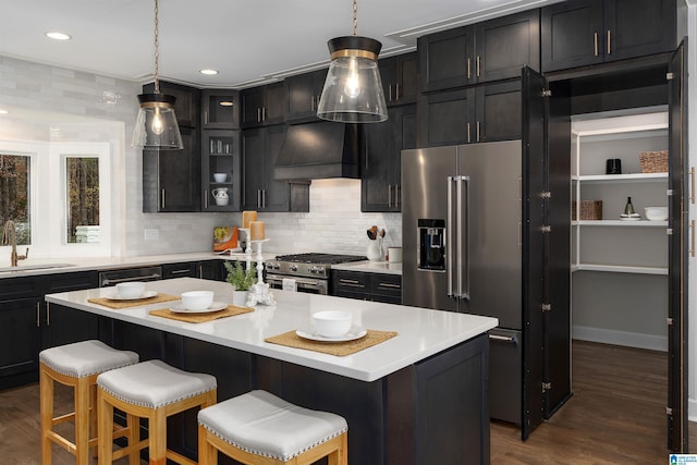 kitchen with custom exhaust hood, high end appliances, light countertops, glass insert cabinets, and a kitchen island