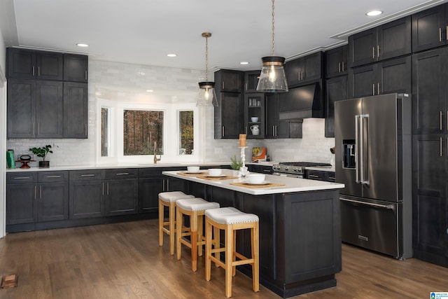 kitchen with high quality appliances, light countertops, a center island, wall chimney exhaust hood, and glass insert cabinets