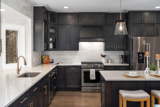 kitchen featuring stainless steel appliances, light countertops, a sink, and custom exhaust hood