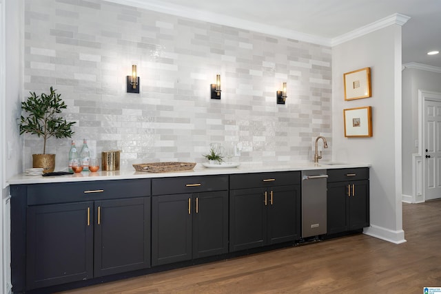 bar featuring wood finished floors, a sink, baseboards, tasteful backsplash, and crown molding