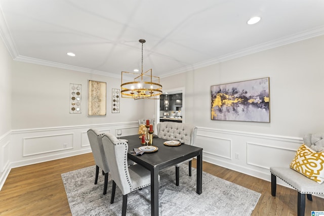 dining space with an inviting chandelier, ornamental molding, wood finished floors, and recessed lighting