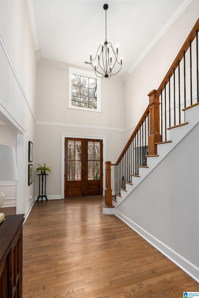 entryway featuring stairway, wood finished floors, crown molding, and french doors