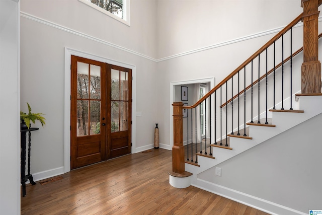 foyer entrance featuring french doors, a high ceiling, baseboards, and wood finished floors