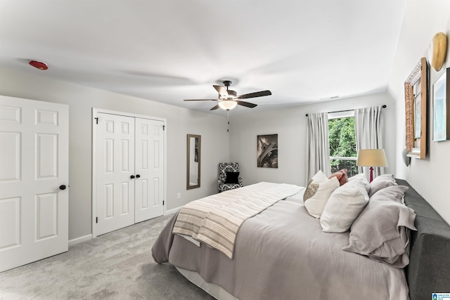 bedroom featuring a closet, light colored carpet, ceiling fan, and baseboards