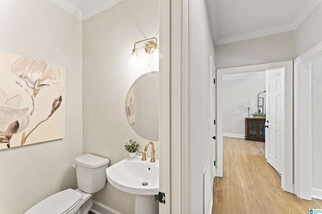 half bath featuring toilet, a sink, ornamental molding, and wood finished floors