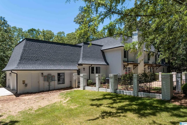 rear view of house with brick siding, a yard, roof with shingles, a garage, and fence private yard