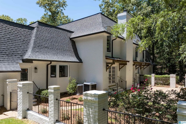 view of front of property with a shingled roof, fence, and brick siding