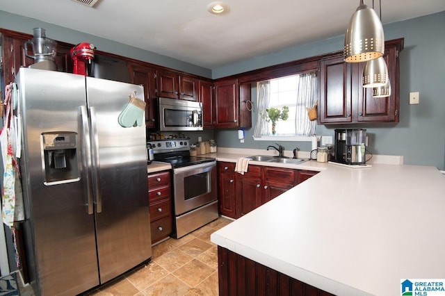 kitchen featuring sink, stainless steel appliances, pendant lighting, and kitchen peninsula