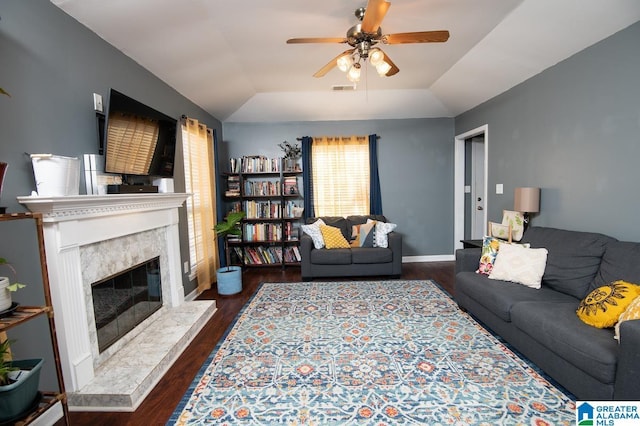 living room with a high end fireplace, ceiling fan, lofted ceiling, and dark hardwood / wood-style flooring