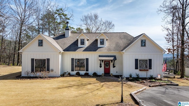 modern inspired farmhouse with a chimney, a front lawn, board and batten siding, and a shingled roof