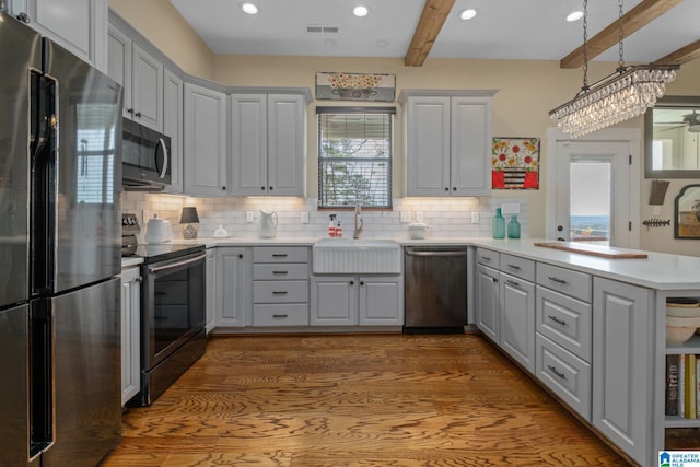 kitchen with gray cabinets, visible vents, appliances with stainless steel finishes, a sink, and a peninsula