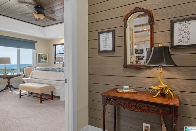 interior space with carpet, wooden walls, stainless steel microwave, and ceiling fan