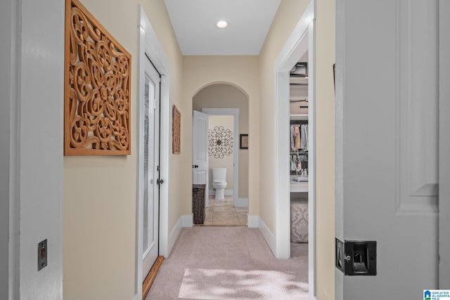 corridor featuring arched walkways, recessed lighting, carpet flooring, and baseboards