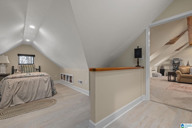 bedroom featuring baseboards, visible vents, vaulted ceiling, and wood finished floors