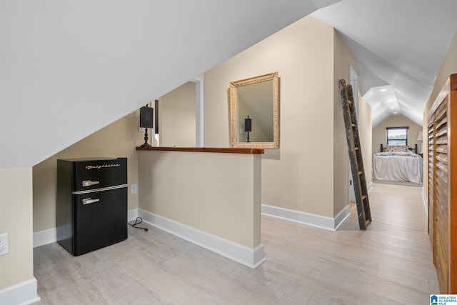 hallway featuring lofted ceiling, light wood-style flooring, baseboards, and recessed lighting