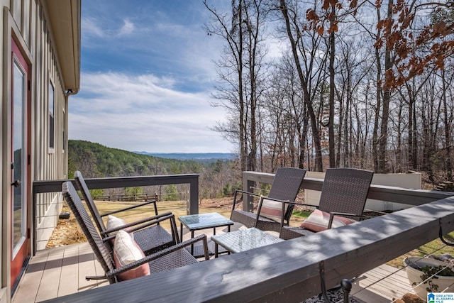 deck with a mountain view, an outdoor living space, and a wooded view