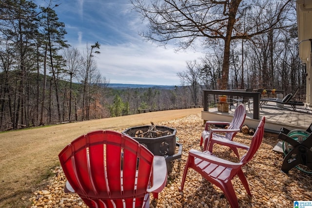 exterior space with a fire pit and a view of trees