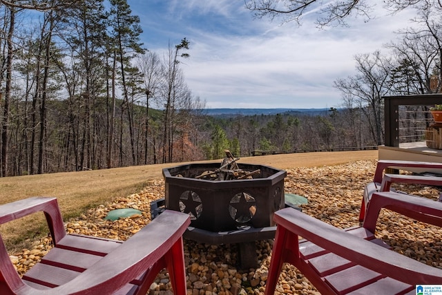 view of yard with a forest view and a fire pit