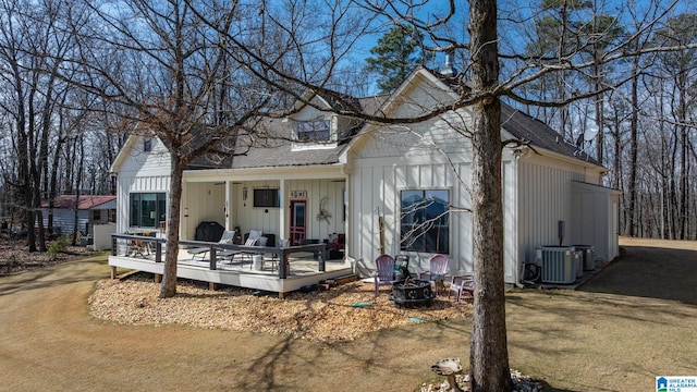 view of front of home with a deck, central AC, an outdoor fire pit, and roof with shingles