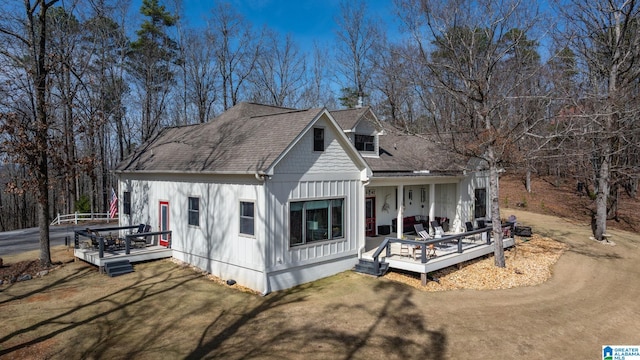 view of front of house featuring board and batten siding, a front yard, roof with shingles, and a deck