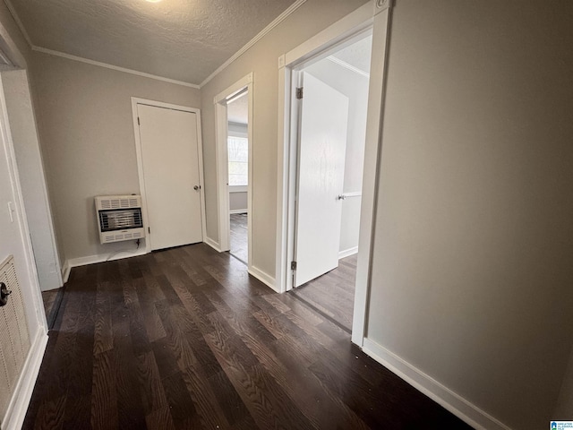 hallway featuring a textured ceiling, baseboards, heating unit, dark wood finished floors, and crown molding