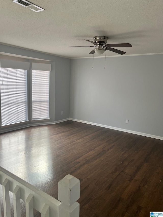 unfurnished room with dark wood-style floors, visible vents, a textured ceiling, and baseboards