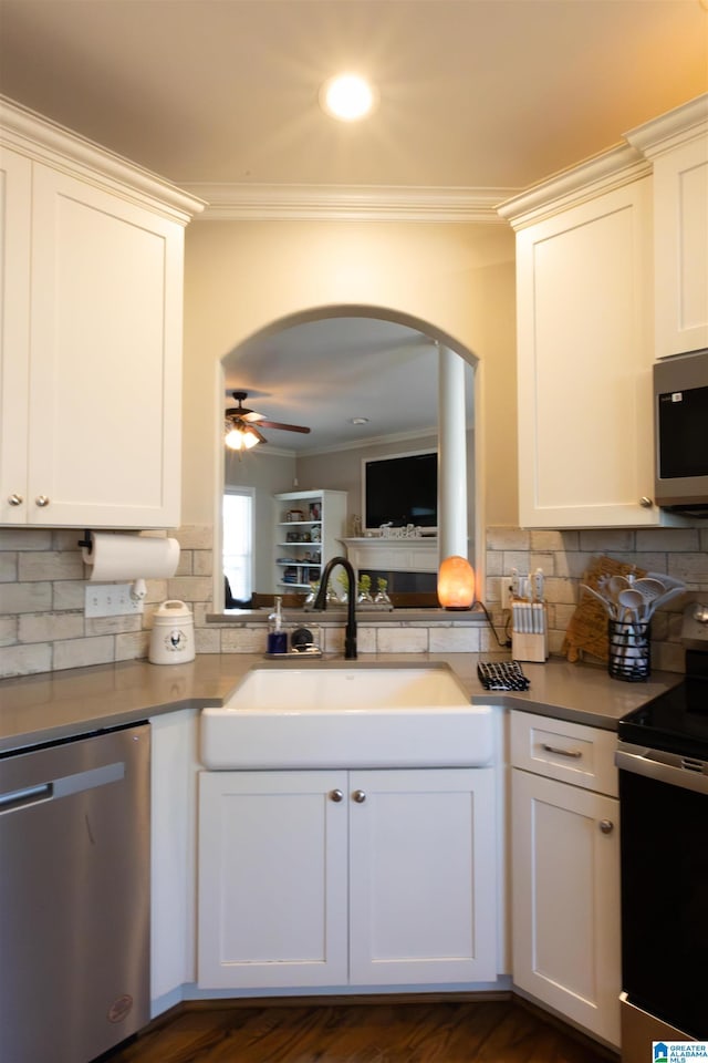 kitchen featuring appliances with stainless steel finishes, crown molding, a sink, and decorative backsplash