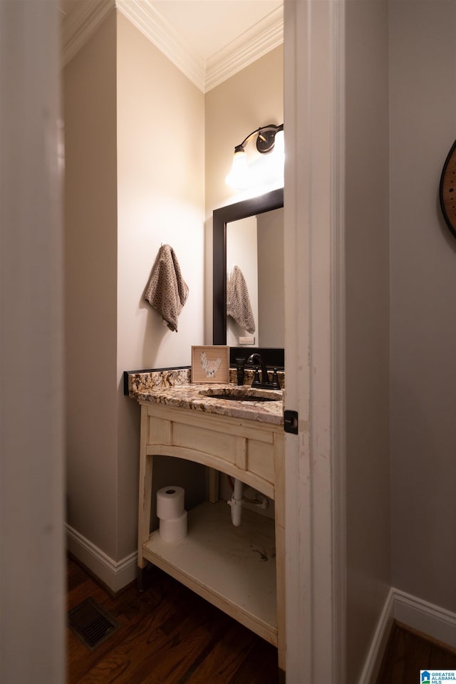 bathroom featuring baseboards, wood finished floors, visible vents, and crown molding