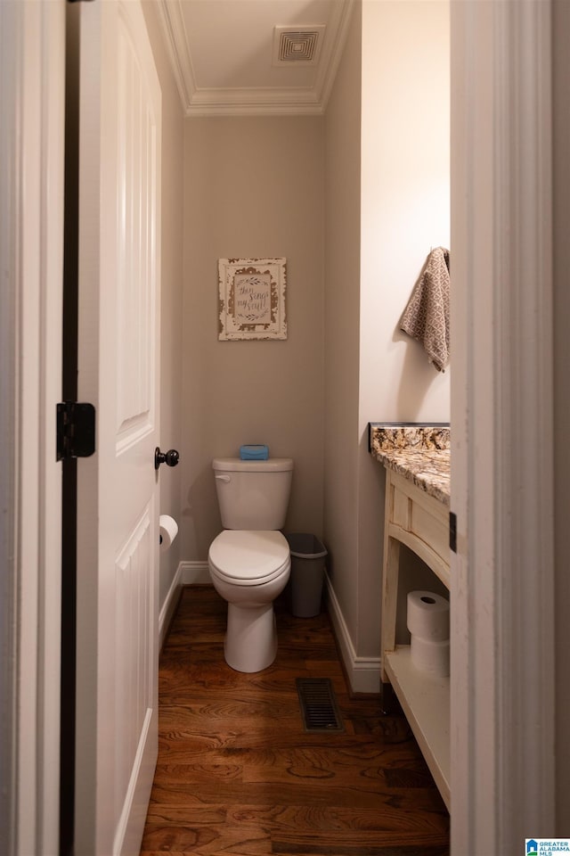 half bathroom featuring toilet, ornamental molding, wood finished floors, and visible vents